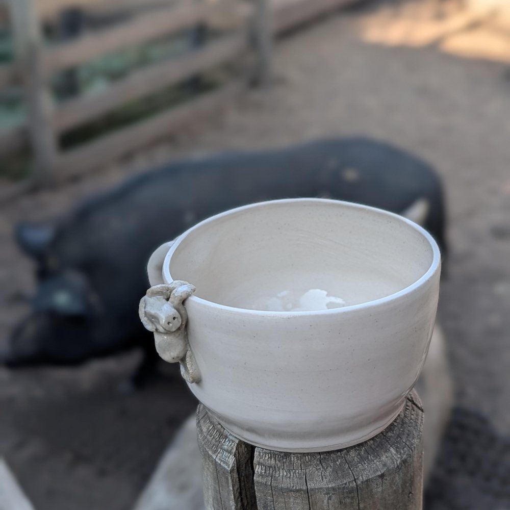 White clay mug with a stone-coloured pig hanging over the rim
